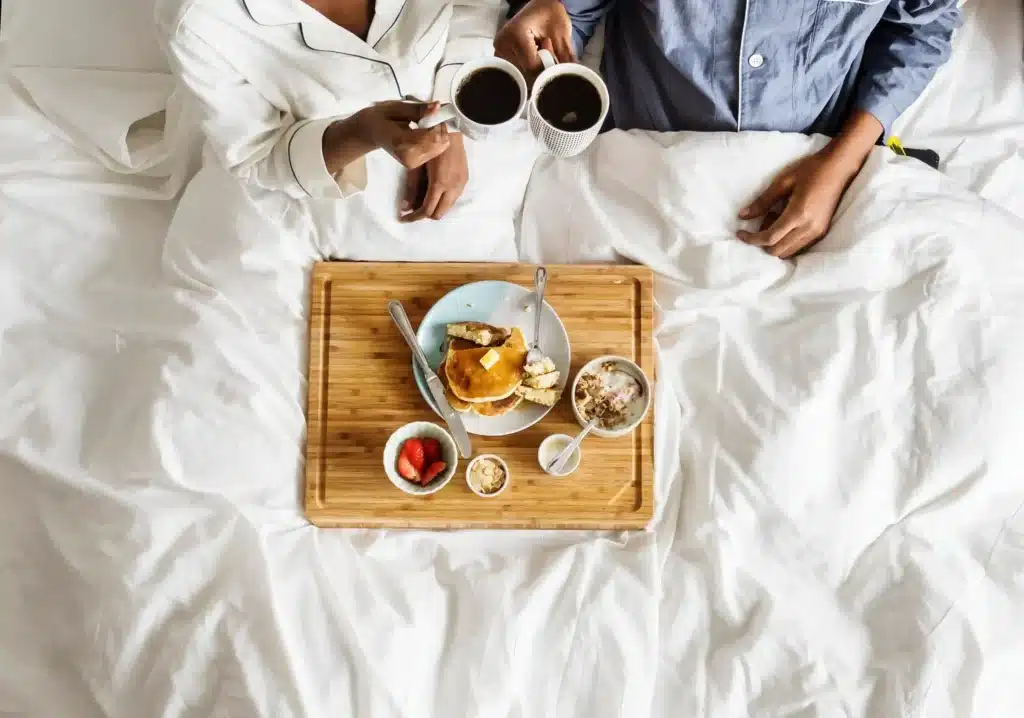 couple heureux qui prends son petit deujeuner au lit