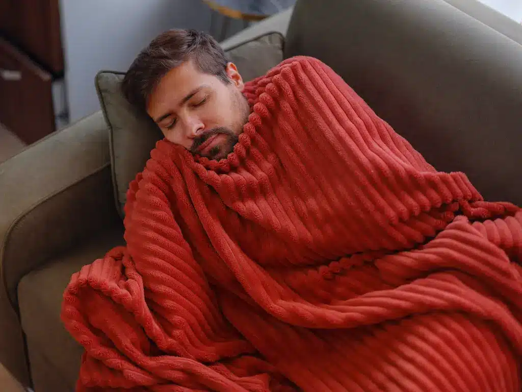 homme qui dort avec une couverture rouge chauffante