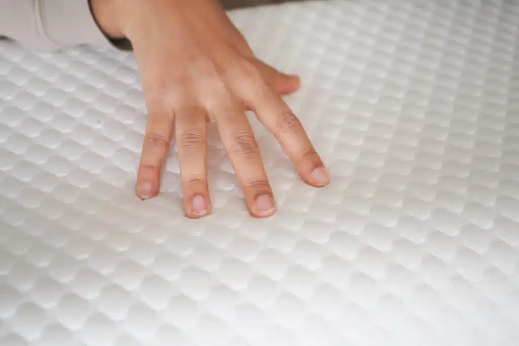 femme qui test la fermeté d'un matelas avec sa main